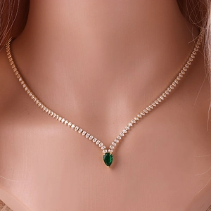 Detail of necklace with gold chain and pear-cut green gemstone with clear crystals