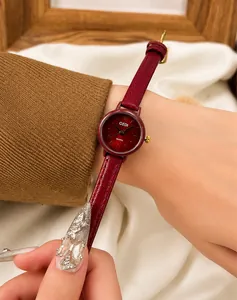 Détail d'une montre à quartz pour femme avec bracelet en cuir rouge et boucle dorée