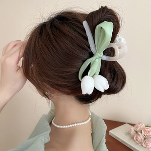 Detail of tulip bow hair claw clip showing a French-style bun on a female model