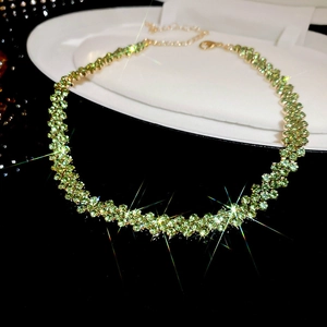 Detailed view of green crystal choker with gold chain and lobster clasp on black background
