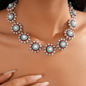 Detailed close-up of retro floral necklace with pearls, turquoise beads and red rhinestones