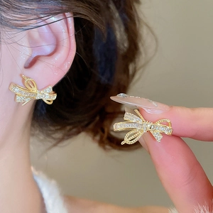 Close-up of gold-plated bow earrings with micro-set zircon stones and twisted rope edges