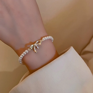Close-up of gold plated bow pearl bracelet with sparkling zircon on a woman's wrist