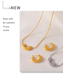 Detailed view of U-shaped pendant necklace and earrings set in gold and silver finish