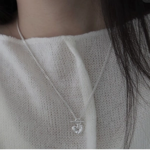 Detail of S925 sterling silver heart pendant necklace with OT buckle on a model