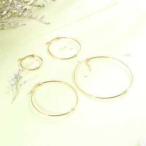 Set of four minimalist gold stainless steel hoop earrings in various sizes on green background