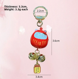 Detail view of red lucky cat bell keychain with gold lucky charm and premium metal finish