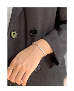 Detail of silver twisted bracelet and chain ring set worn with a black formal blazer