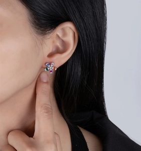 Detail of floral silver stud earrings with colorful zircons on a model's ear