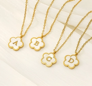 Detail of 18K gold plated necklaces featuring shell flower pendants with A-D initials