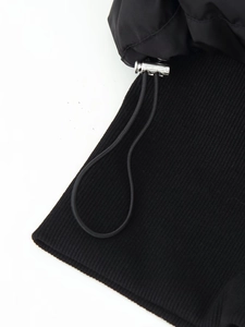 Detail of silver drawstring toggles and ribbed knit texture on a black puffer jacket