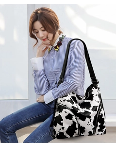Close-up of stylish cow print shoulder bag with zipper detail on a casual model