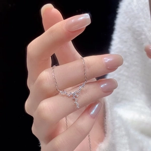 Silver star necklace with zircons shown by hand against a black background