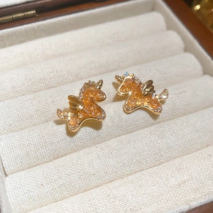 Macro shot of gold-plated unicorn stud earrings with amber cubic zirconia crystals