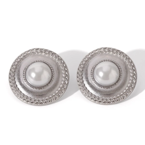 Detail view of silver vintage earrings with a white pearl and woven metal texture