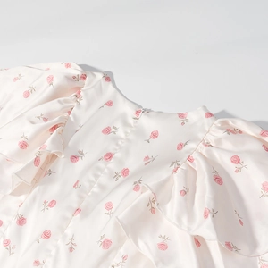 Détail de la manche à volants et de l'imprimé floral rose sur la robe en satin à col en V