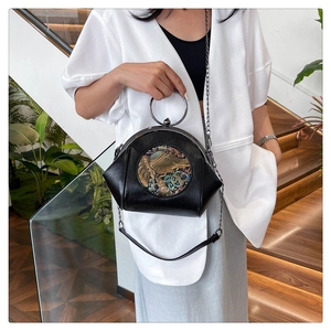 Detail of a vintage black shell bag featuring golden elephant relief and metal chain handle