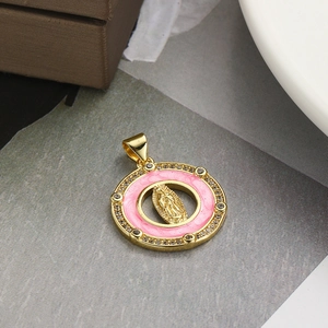 Macro detail of a golden Virgin Mary pendant with pink enamel and zircon inlay