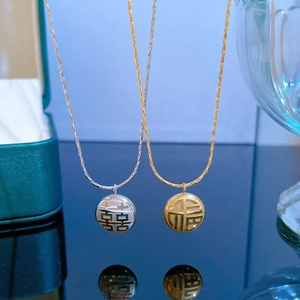 Détail macro des colliers en acier doré et argenté avec pendentifs Fu et Xi chinois
