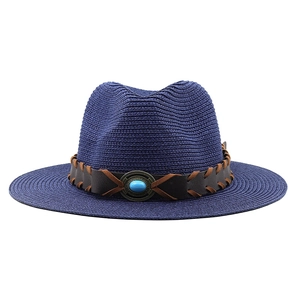 Detailed view of straw fedora hat featuring a turquoise stone and braided leather band