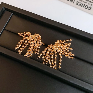 Detailed macro view of gold-plated fan-shaped bead chain tassel earrings on black velvet