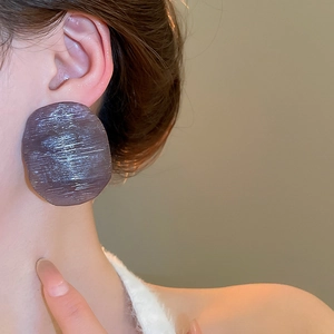 Macro view of dark purple textured resin earrings with horizontal brushed pattern on model