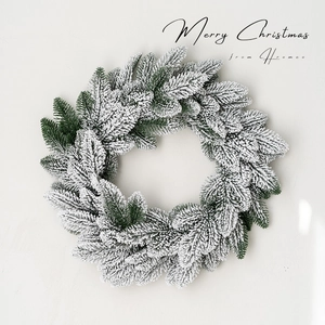 Close-up of a frosted Christmas wreath with snow-flocked pine needles and Merry Christmas text