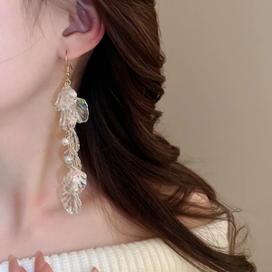 Detail of long fringe drop earrings with iridescent shell-like petals and pearls on model