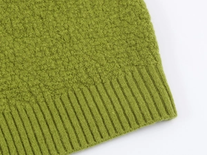 Detailed close-up of grass green knit sweater fabric texture with ribbed hem edges