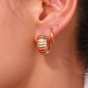 Chic gold hoop earrings with vibrant rainbow enamel stripes worn by a fashion model