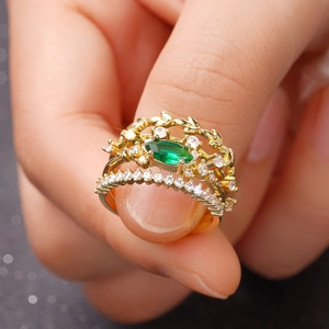 Primer plano detallado de anillos apilables dorados con piedra marquise de color verde