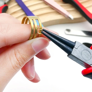 Close-up of multifunctional jewelry pliers opening a jump ring on a gold ring