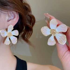 Detail of elegant white flower earrings with gold edges and pink gradient finish