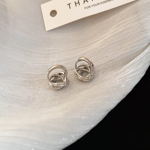 Detail of silver twisted multilayer hoop earrings on elegant white wavy silk fabric