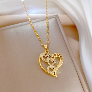 Detail of gold heart pendant with LOVE engraving and three small sparkling inlaid stones