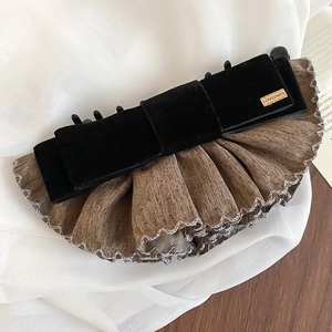 Détail d'une pince à cheveux à nœud en velours avec plaque dorée et tissu plissé élégant