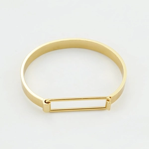 Bracciale rigido in metallo dorato minimalista con un semplice design a cornice