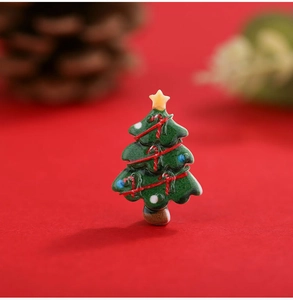 Macro shot of miniature green resin Christmas tree with yellow star and red swirls