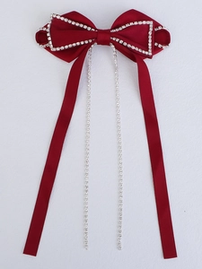 Detail of red satin bow hair clip featuring sparkling silver rhinestone fringe on white background