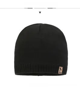 Close-up of black ribbed knit beanie featuring a brown brand leather patch on the hem
