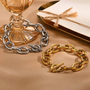 Detail of gold and silver chunky chain bracelets with OT toggle clasps on texture