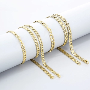 Polished gold Cuban link chains in various sizes draped on a white column prop
