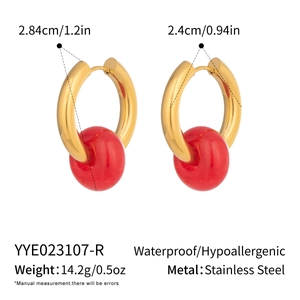 Macro detail of waterproof stainless steel gold hoops with red sphere pendant