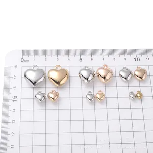 Polished silver and gold heart pendants in five sizes on measuring grid for DIY jewelry