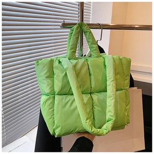 Detail of bright green quilted puffer tote bag with soft padded texture and top handle