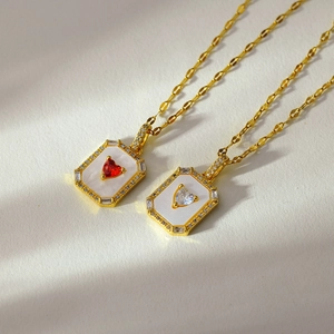 Detailed view of rectangular gold-plated necklaces with heart stone and mother of pearl