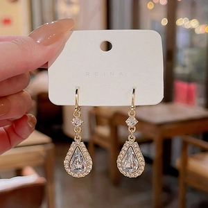 Macro detail of golden teardrop earrings with pear-cut crystals and pavé cubic zirconia