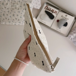 Close-up of small cotton makeup bag featuring heart patterns and a golden zipper detail