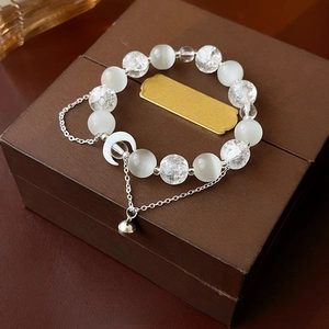 Detailed shot of moon pendant and cat eye beads on a silver beaded bracelet