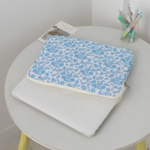 Close-up of quilted floral blue tablet sleeve with zipper on a sleek laptop